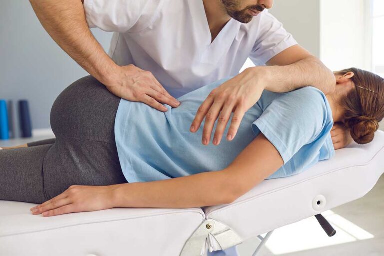 Person doing gentle stretches on a living room mat with a pillow for lower back support.