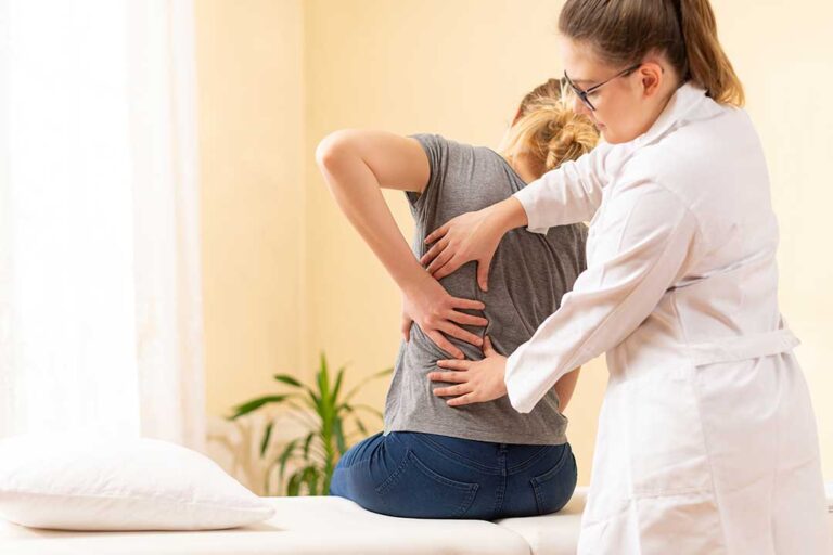A chiropractor discussing spine health with a patient during an initial health consultation.